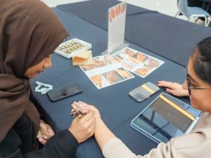 Two university students do crafts at a table during an international student event.