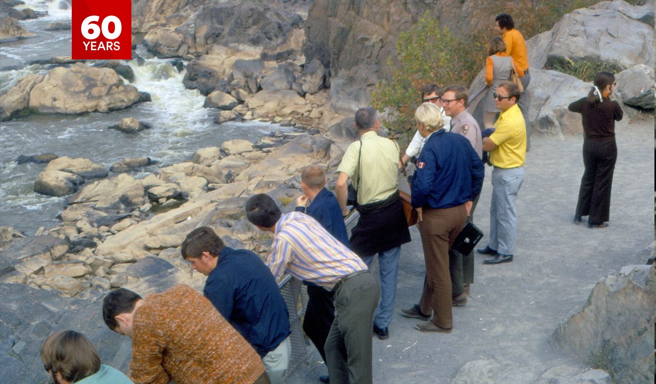 Brock students completing fieldwork in the Ottawa Valley observe a waterway from a rocky vantage point while conferring with a local official.