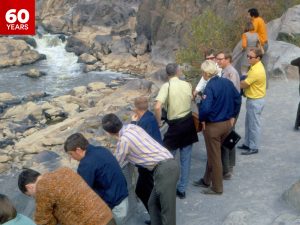 Brock students completing fieldwork in the Ottawa Valley observe a waterway from a rocky vantage point while conferring with a local official.