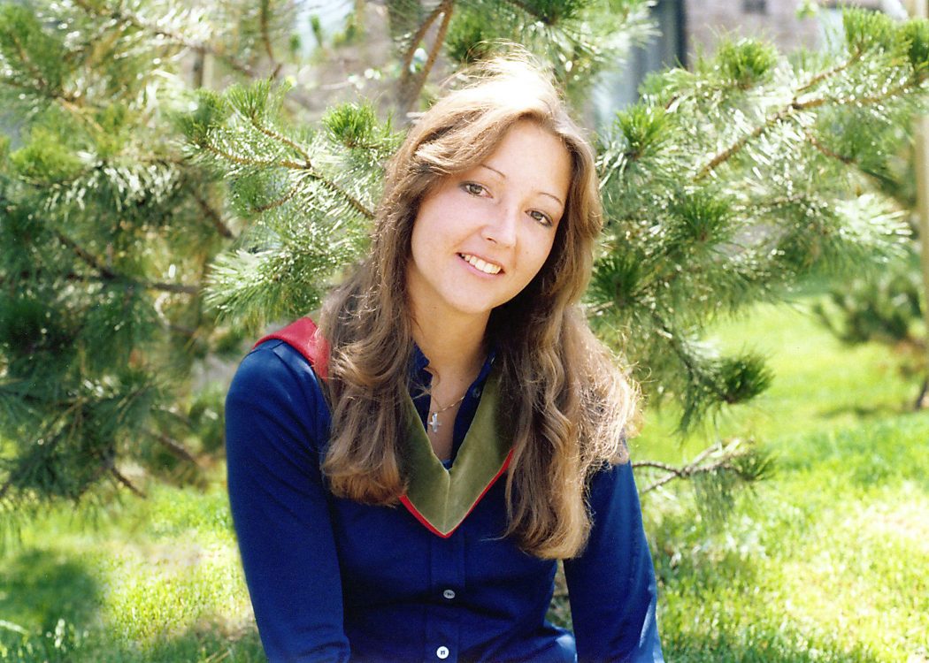 A young woman poses for a photo in front of a tree. 