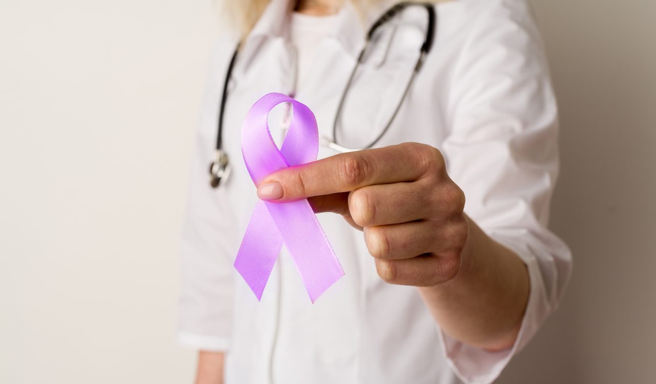 Medical professional in navy blue scrubs holds a purple ribbon for overdose prevention awareness.