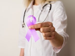 Medical professional in navy blue scrubs holds a purple ribbon for overdose prevention awareness.