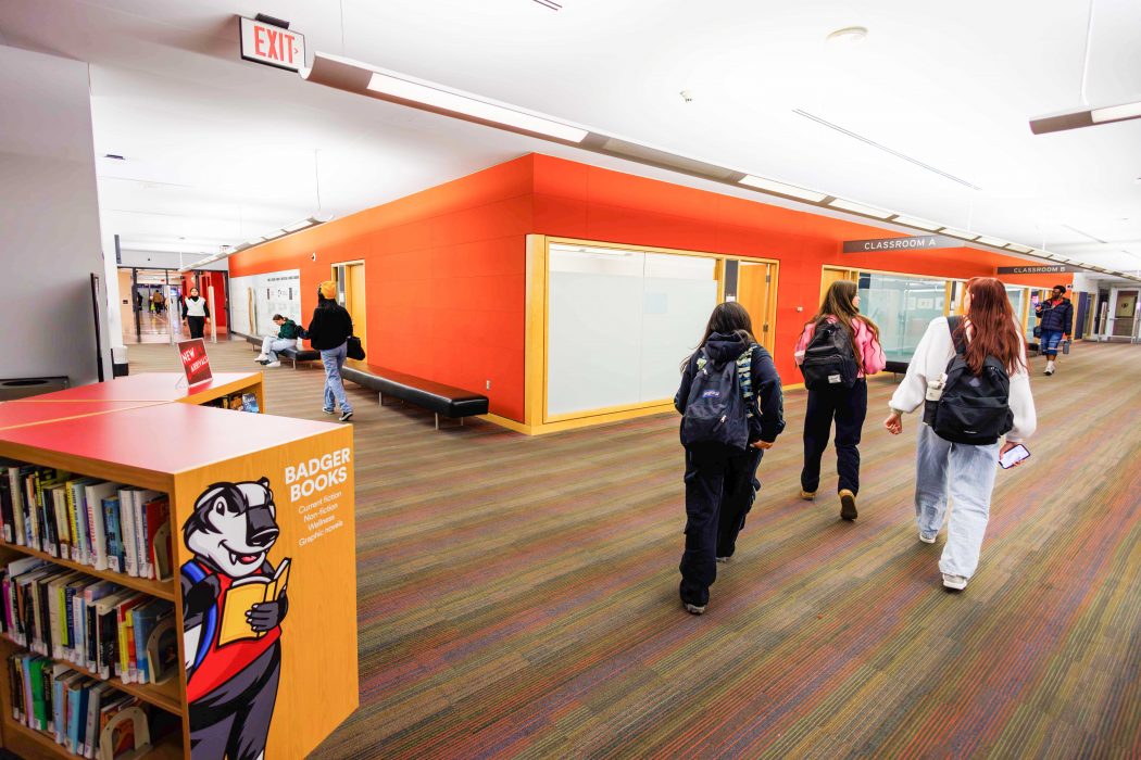 Students walk through a library space with bright lights and colourful study spaces at Brock University.