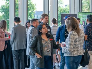 A group of people chat in a brightly lit room at a networking event.