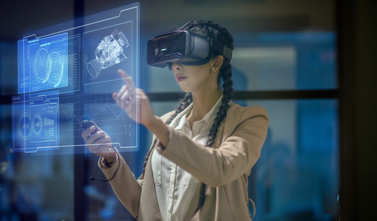 A woman wearing a VR headset manipulates glowing icons and illustrations floating in front of her.