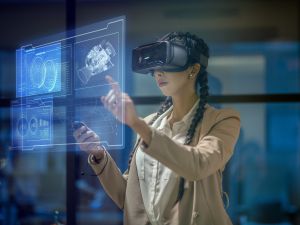 A woman wearing a VR headset manipulates glowing icons and illustrations floating in front of her.