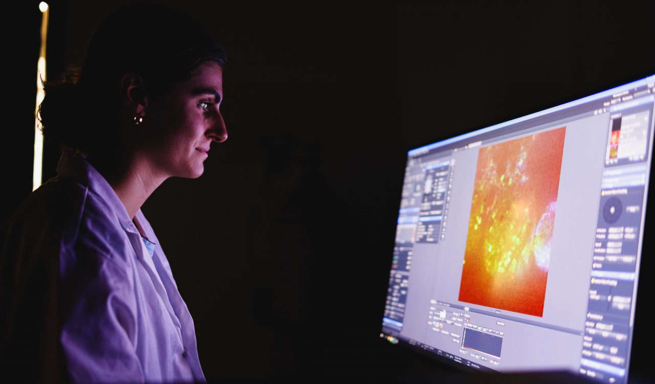 A woman scientist looks at a computer screen in a dark room.