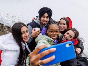 A group of university students take a selfie outside in the snow.