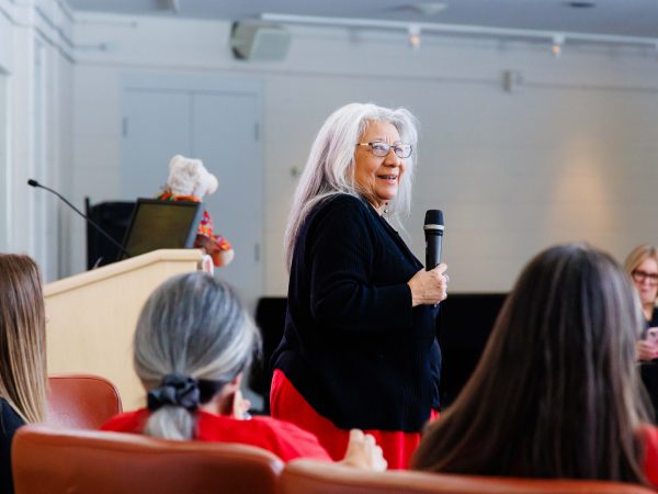 A woman wearing black stands in front of a crowd while smiling and holding a microphone at Brock University.