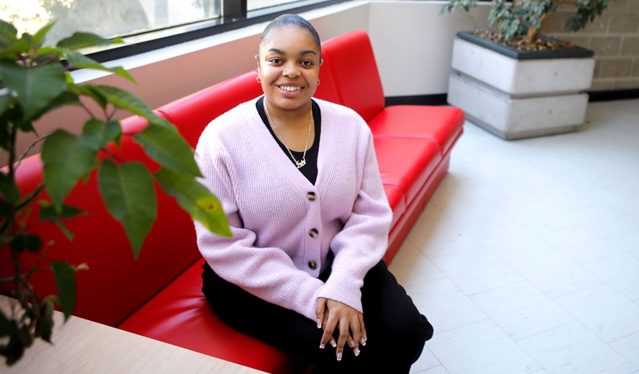 Woman in purple sweater sits on a red bench.