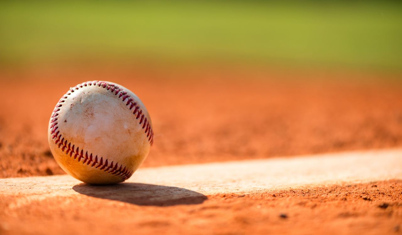 Close-up pf a baseball sitting on the ground.