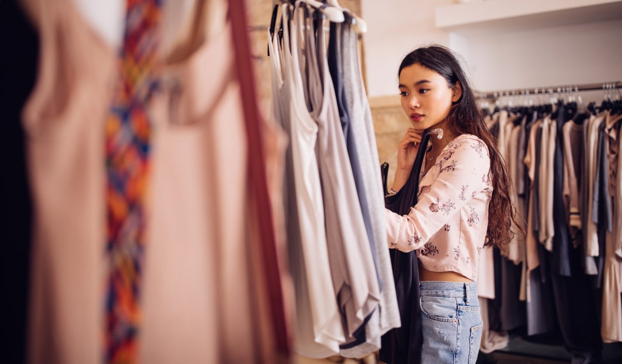A young woman browsing through summer clothes in a clothing store.
