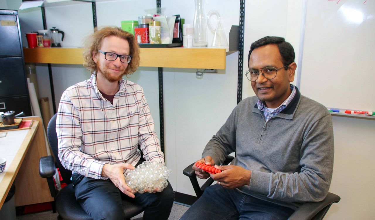 PhD physics student Connor Wilson (left) and Assistant Professor of Physics Ganesh Ramachandran (right) sit next to each other in an office.
