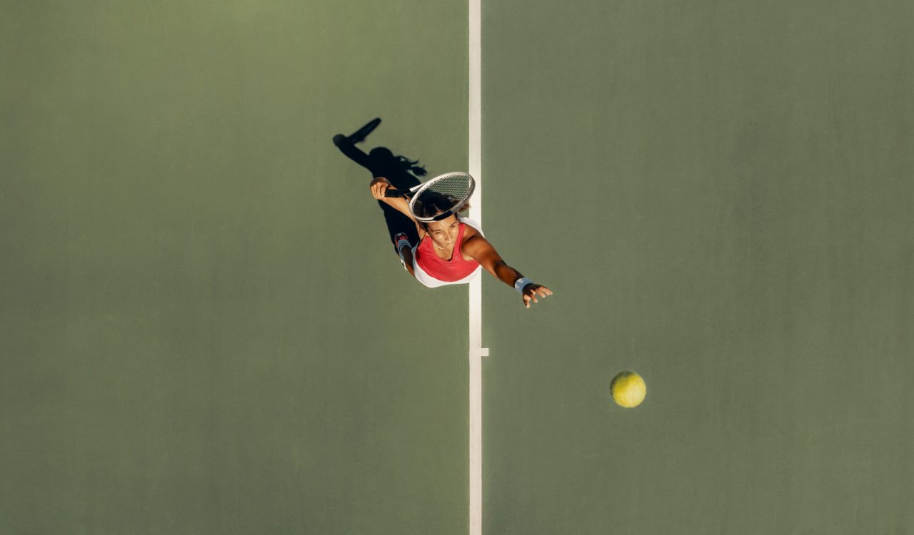 A woman, seen from above, prepares to hit a tennis ball while serving.
