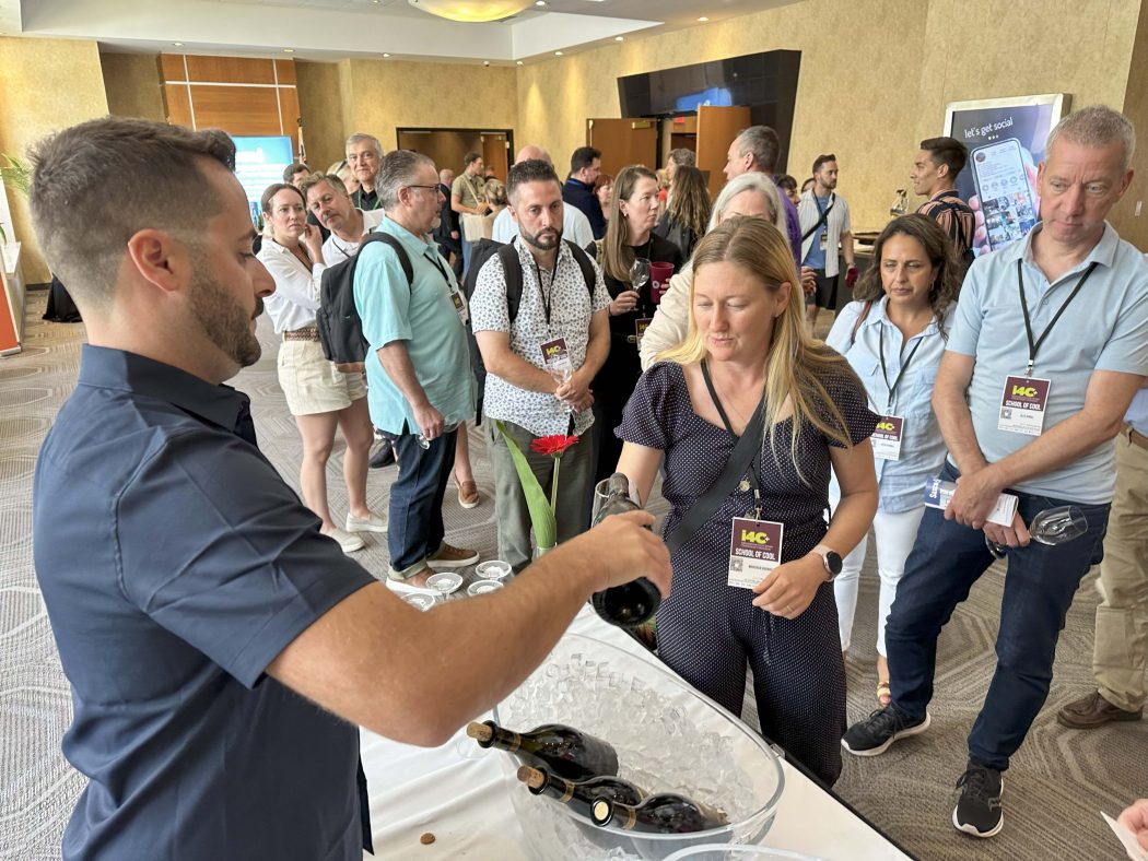 A man pours wine tastings for a long line of waiting wine lovers.