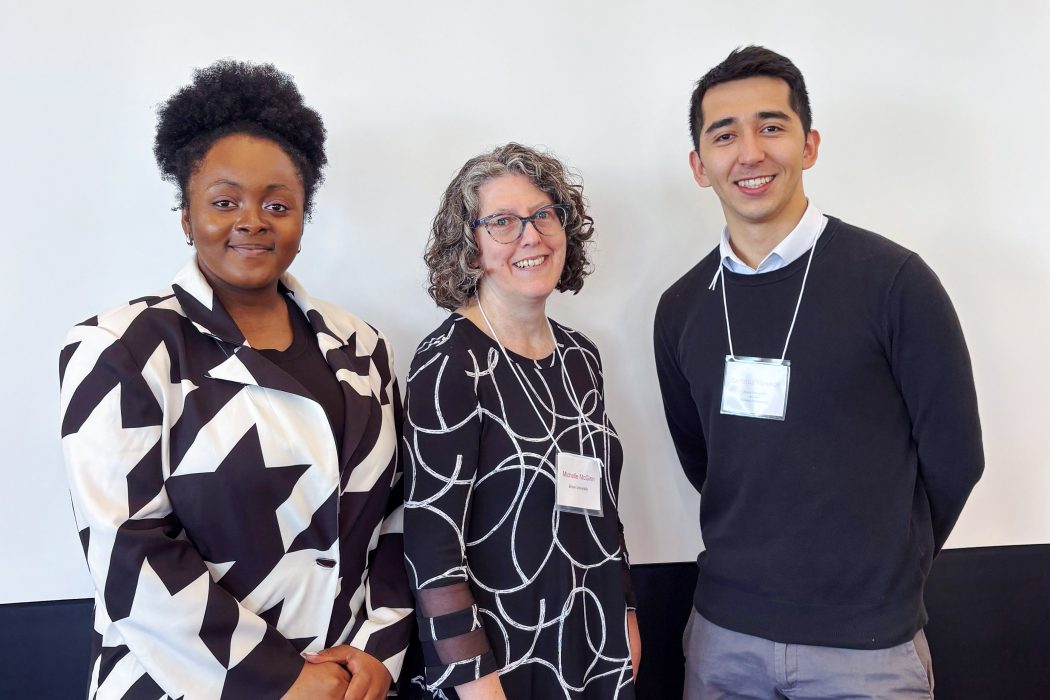 Chimerem Amiaka (left), Michelle McGinn (centre) and Sarfaroz Yunusov (right) stand in front of a white screen.