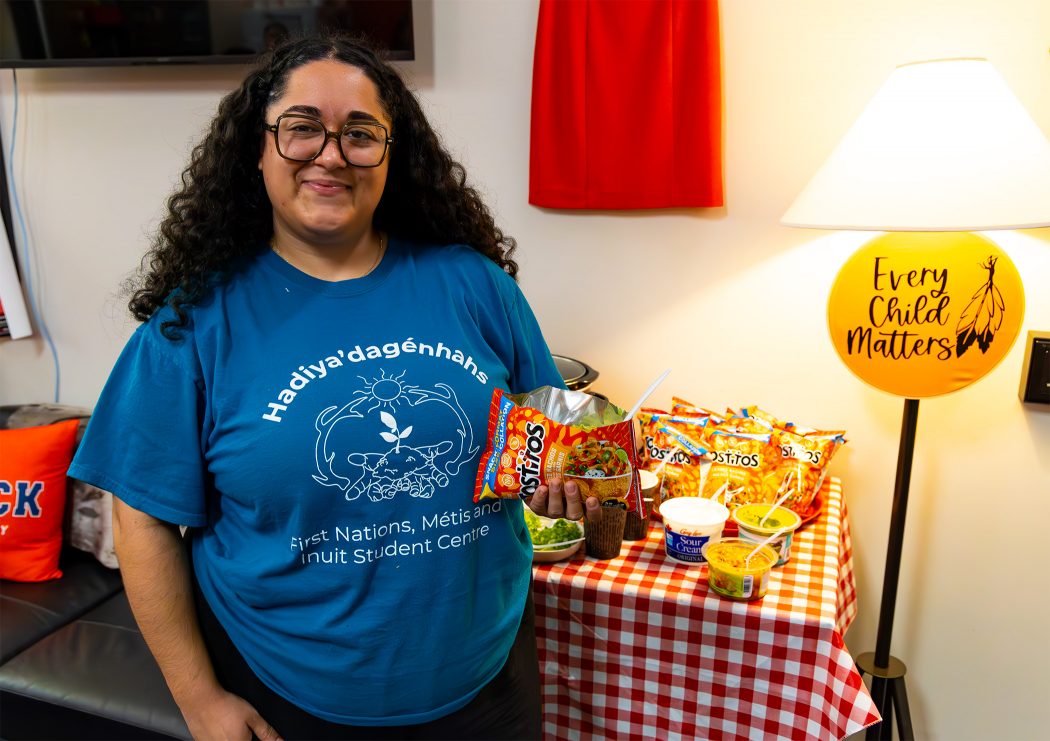 A young woman holds up a bag of chips.