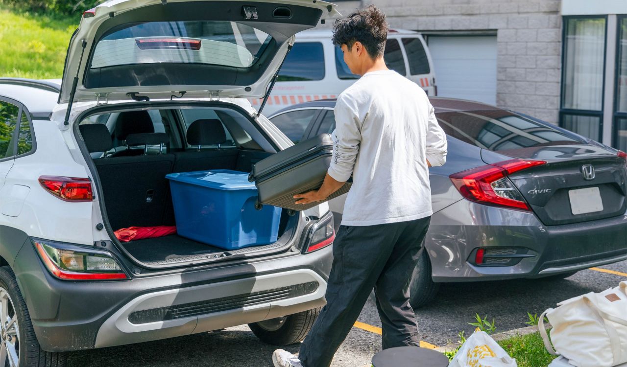 A person unloads storage totes from the back of a car.