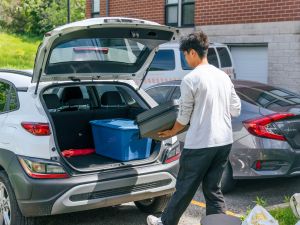 A person unloads storage totes from the back of a car.
