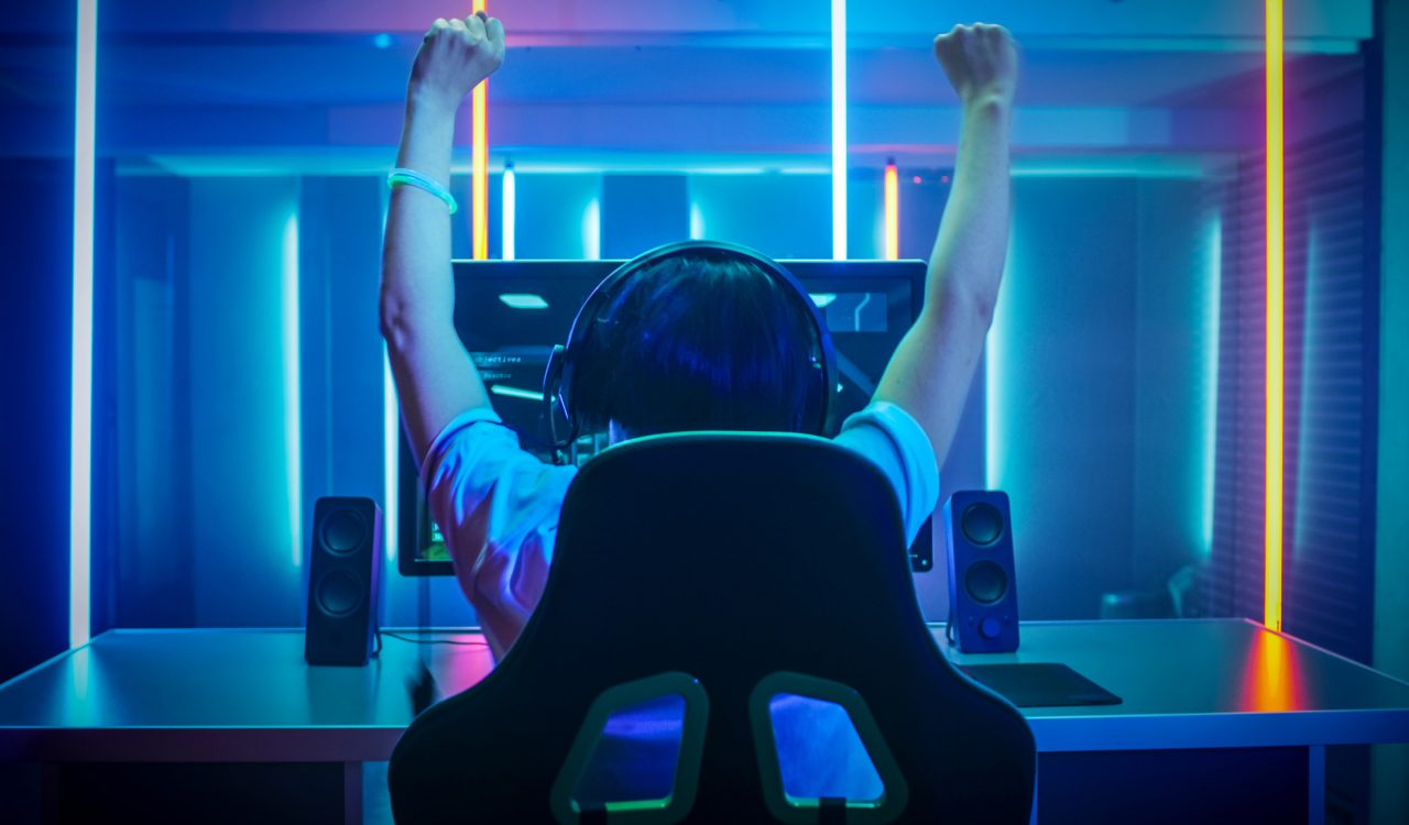 A person playing a video game raises their hands in the air after winning.