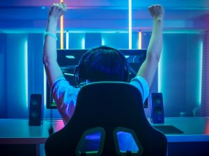 A person playing a video game raises their hands in the air after winning.