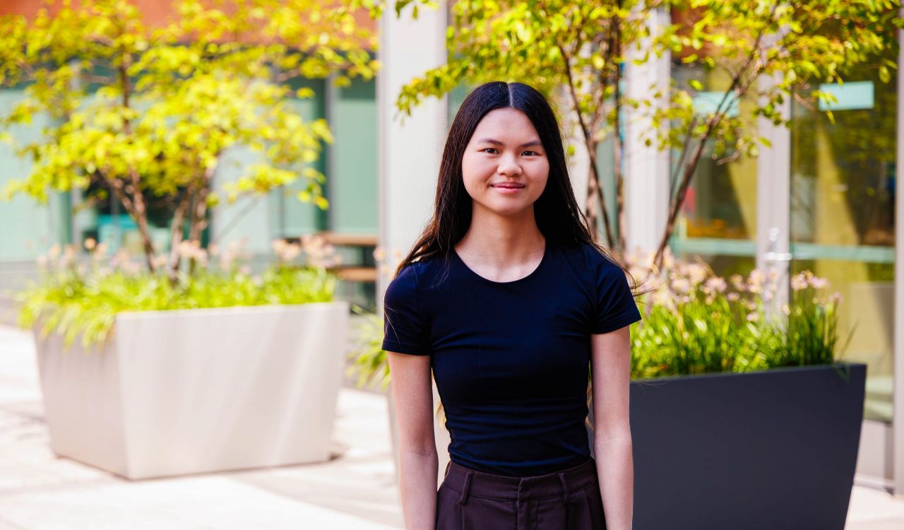 A woman poses for a photo outside in a courtyard.