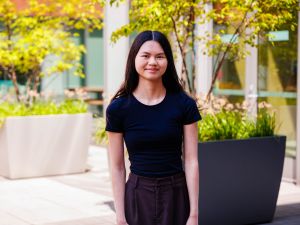 A woman poses for a photo outside in a courtyard.