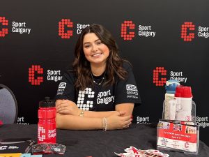 A smiling woman works at a booth during a sporting event.