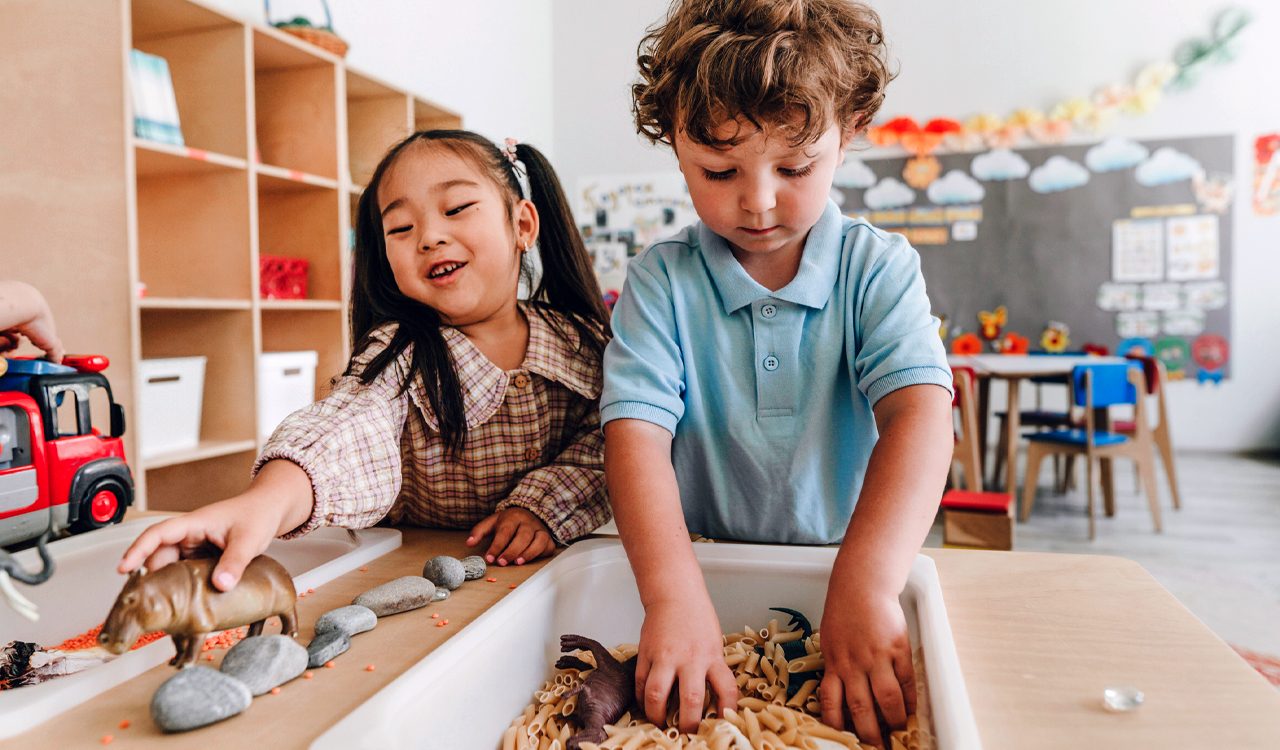 Boy and girl play with a sensory bin in a school classroom.