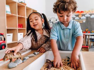 Boy and girl play with a sensory bin in a school classroom.