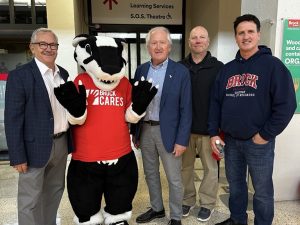 Four men pose for a photo Boomer the Badger, Brock University's mascot.
