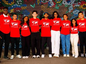 Brock International Student Ambassadors gather for a group photo, proudly wearing their red team shirts in front of a vibrant mural.