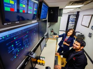 Two people look at a wall of screens.