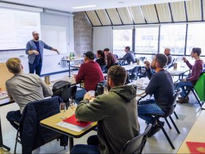 A group of people in a classroom taste cider during a training session.