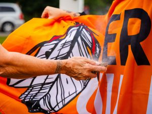 A smudging ceremony blesses the Every Child Matters flag before raising.
