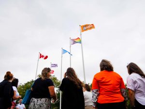 Attendees watch as the Every Child Matters flag flies alongside others.