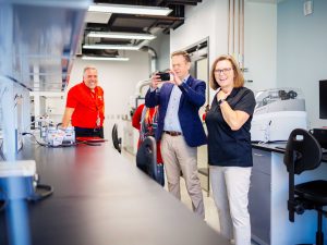 Man taking a photo in a science lab with two colleagues smiling nearby.