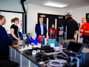 Group listening to a presentation in a research lab with equipment on the table.