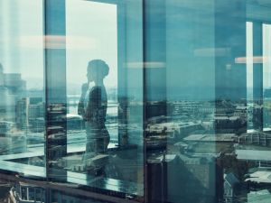 A silhouette of a business woman seen through the window of an office building.