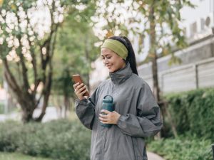 A woman looks at her phone while walking outside.