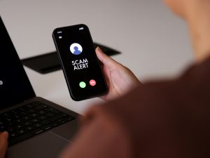 Close-up of hands holding a phone with "scam alert" on its screen.