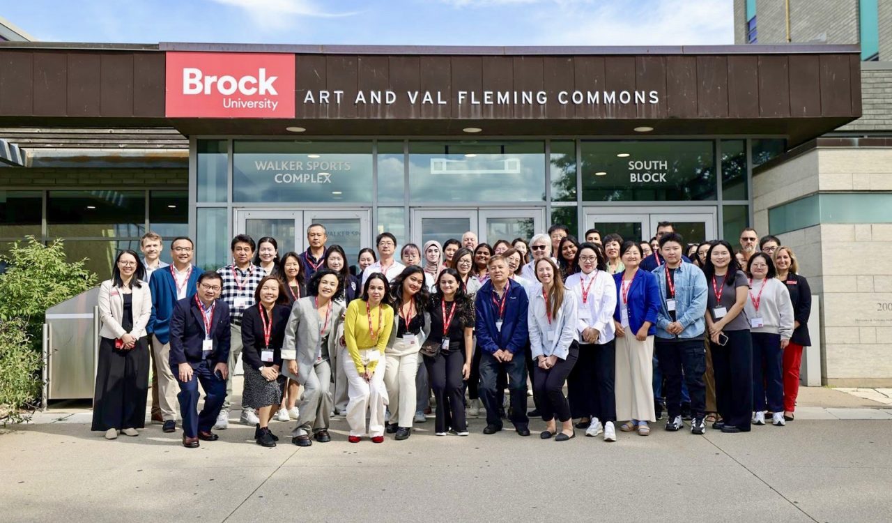 A large group of people pose outside a building.