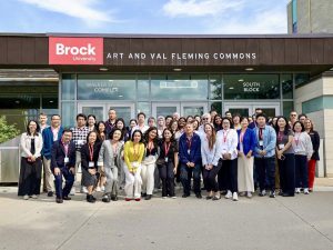 A large group of people pose outside a building.