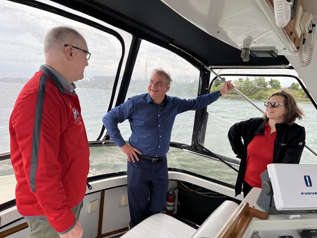Three people stand on a boat.