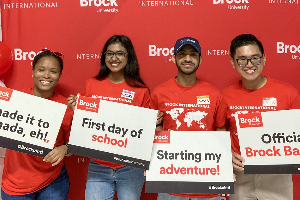Four university students hold up prop signs at a photo booth.