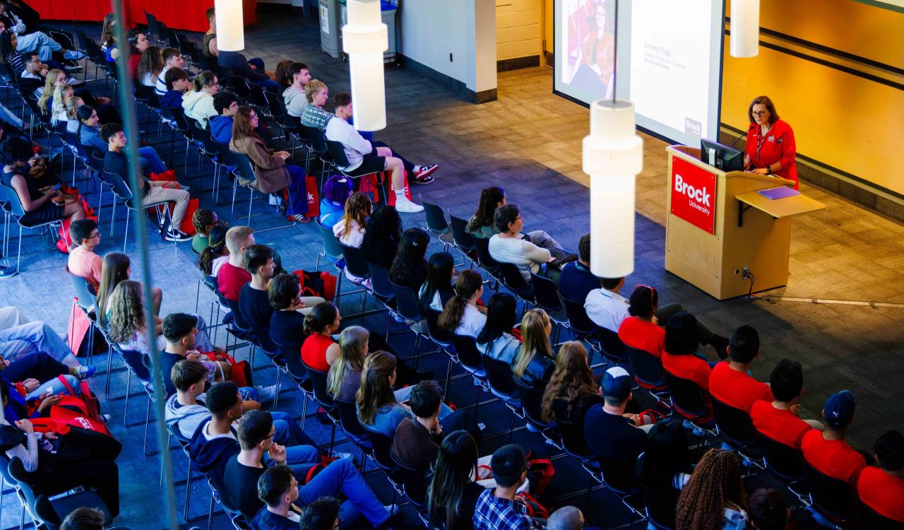 A woman addresses a large audience at an event.