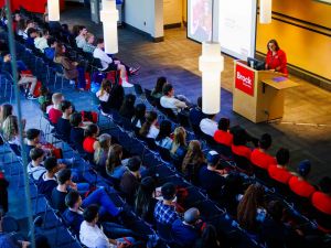 A woman addresses a large audience at an event.