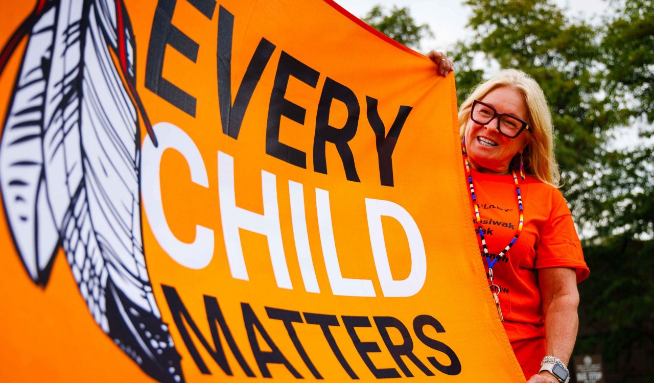 A participant smiles while holding the Every Child Matters flag.