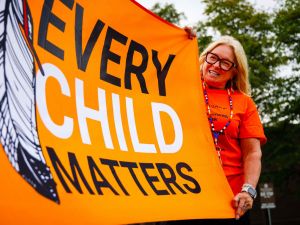 A participant smiles while holding the Every Child Matters flag.