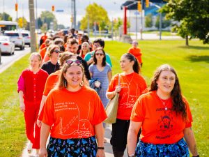 Members of the Brock University community in orange shirts walk together on Brock’s campus.